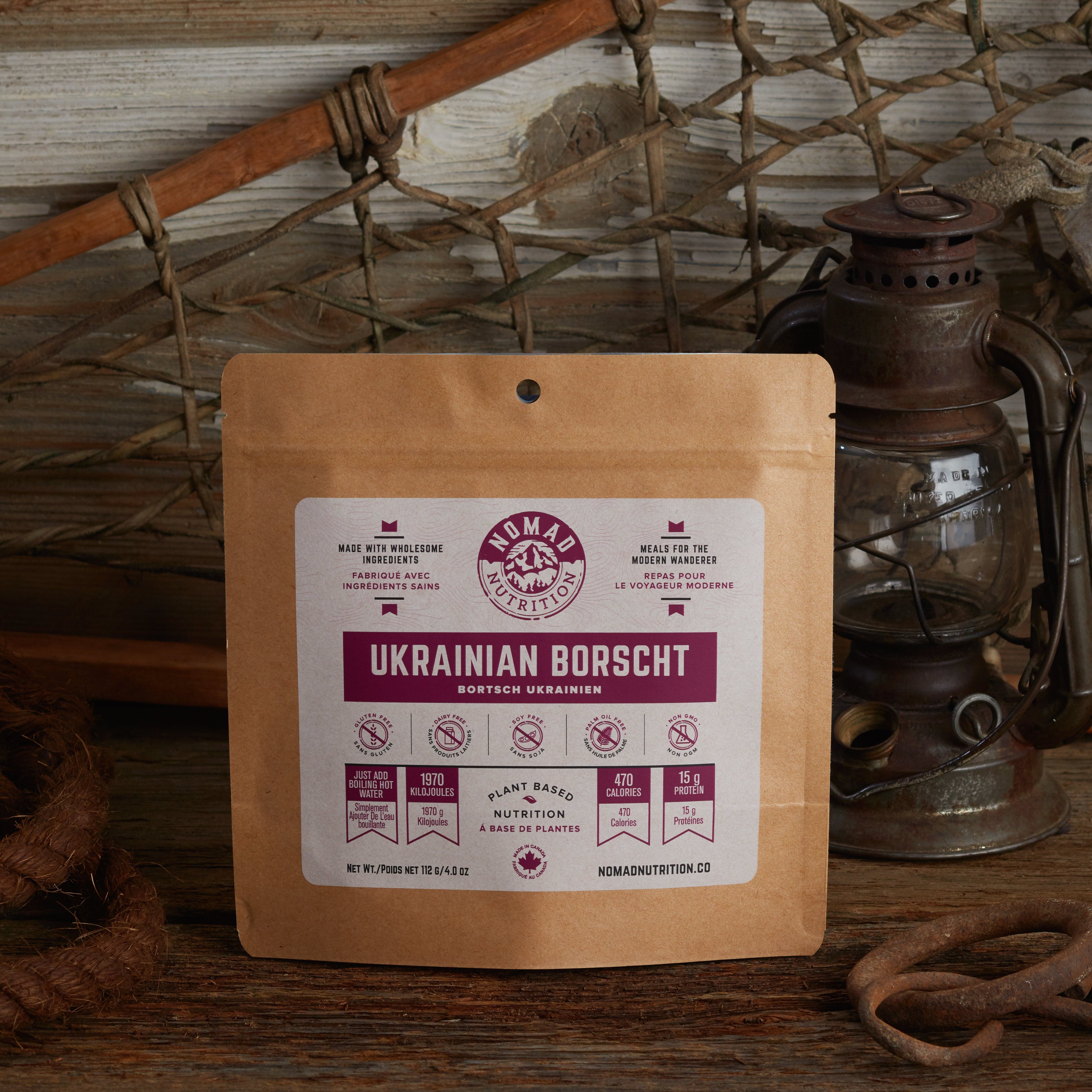 Nomad Nutrition Ukrainian Borscht 112g meal size with outdoor equipments on table top.