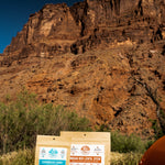 Nomad Nutrition Carribean Curry (56g/ 2oz) and Indian Red Lentil Stew (112g/ 4oz), dehydrated vegan adventure plant-based, gluten-free meal at Arches National Park with canyons visible in the background.