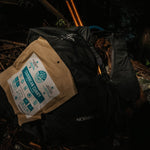 Nomad Nutrition Carribean Curry, vegan dehydrated, gluten-free, plant-based adventure meal pictured with bagpack and trekking poles for an outdoor hiking activity.