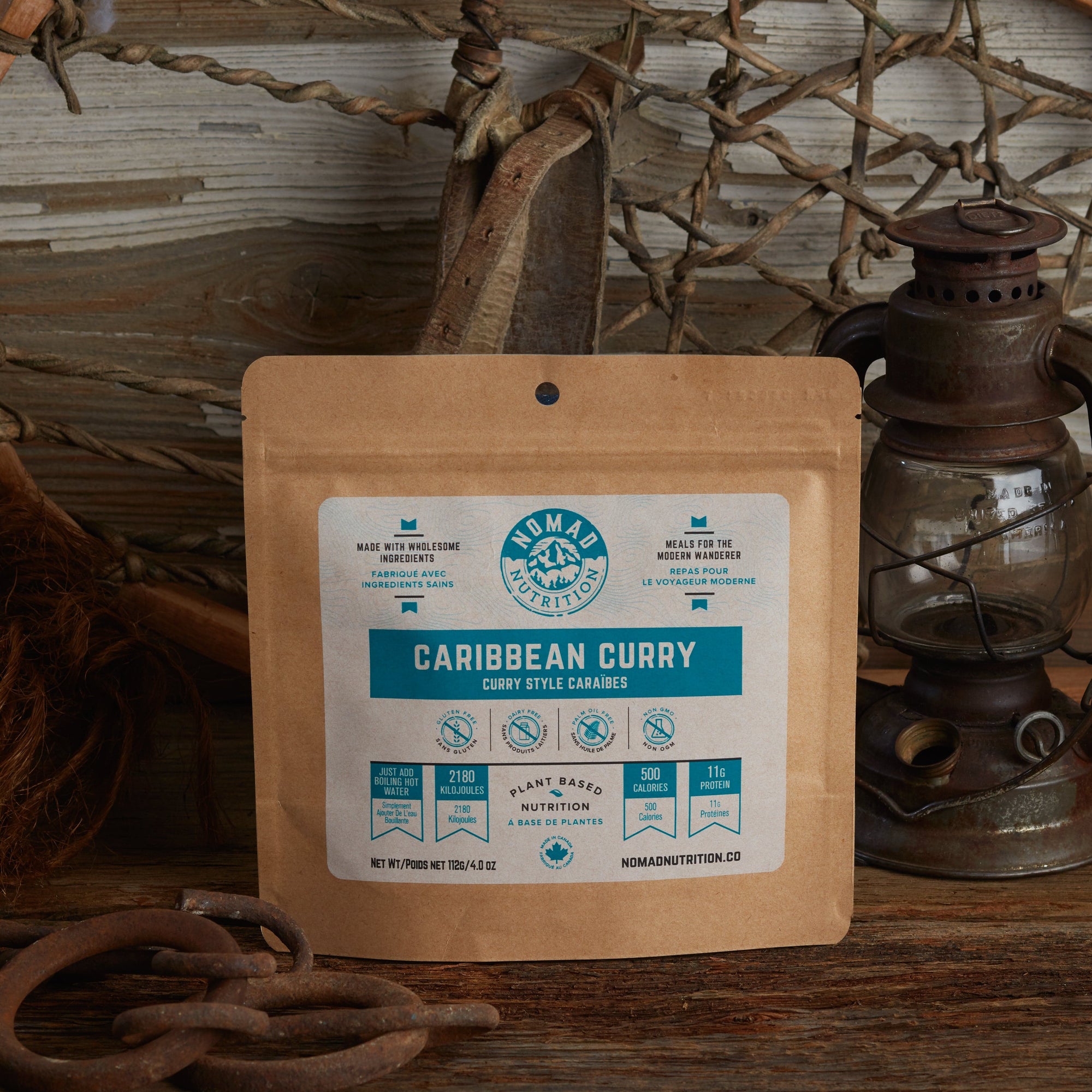 Nomad Nutrition Caribbean Curry 112g meal size with outdoor equipments visible on table top.