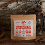 Nomad Nutrition Indian Red Lentil Stew 112g meal size with outdoor equipments on table top.
