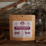 Nomad Nutrition Ukrainian Borscht 112g meal size with outdoor equipments on table top.