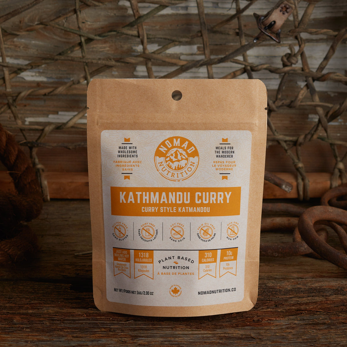 Nomad Nutrition Kathmandu Curry 56g snack size with outdoor equipments on table top.